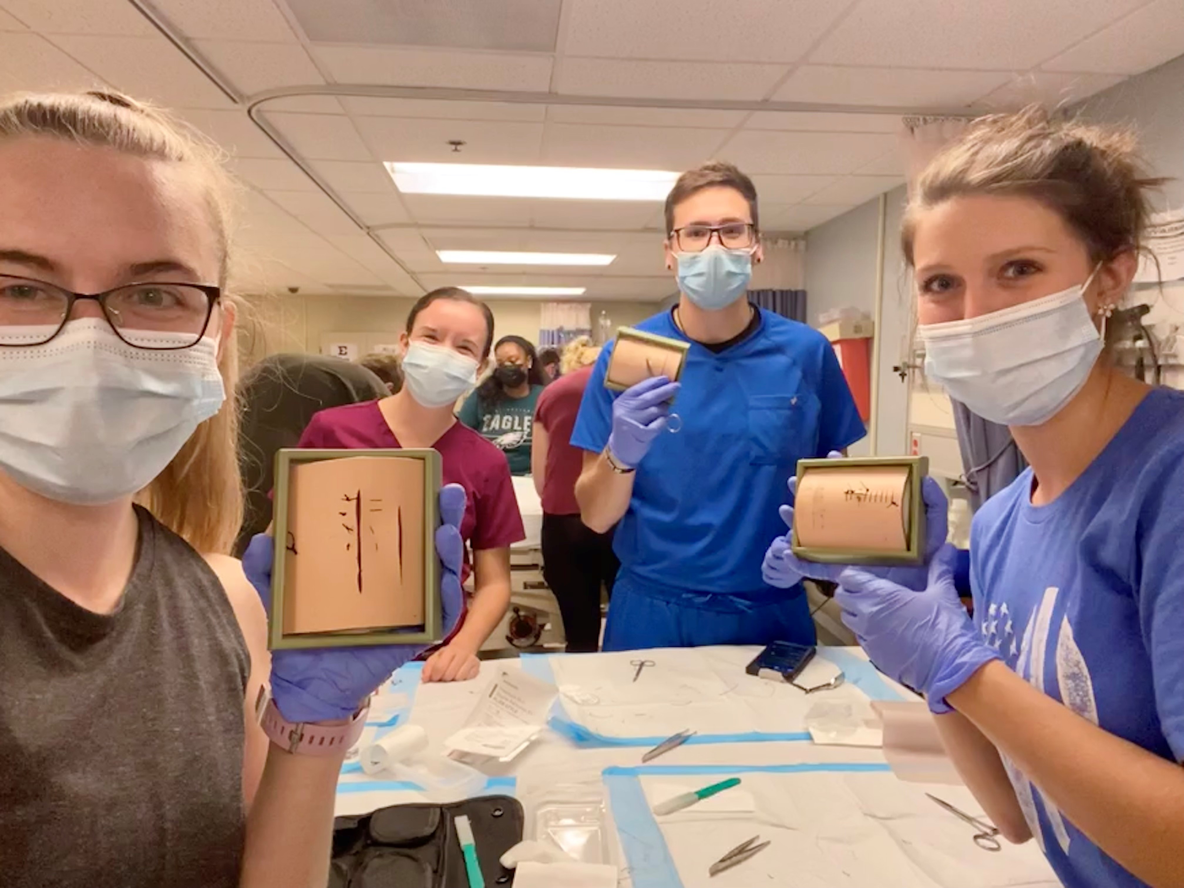 PA Student Jen Ensor with fellow students displaying suture practice